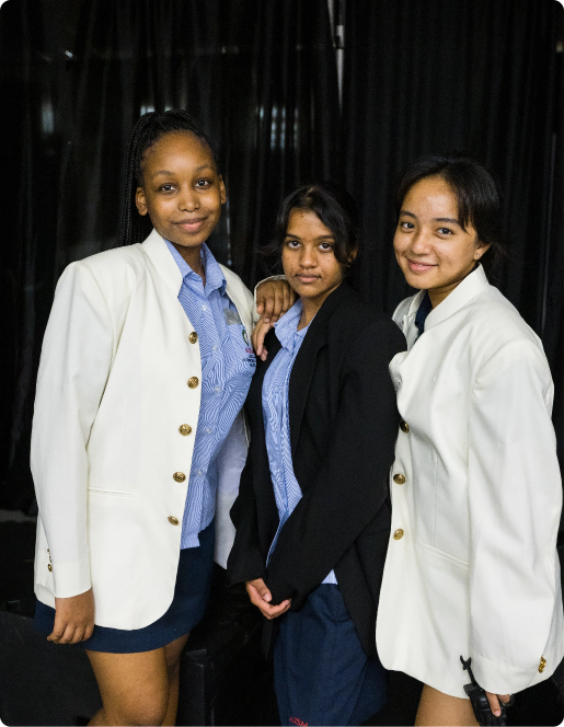 Three young students in school uniforms stand together.