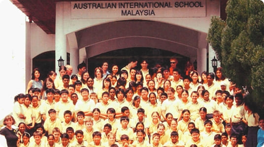 Group photo of AISM students and staff in yellow uniforms, from the founding year in 2000.
