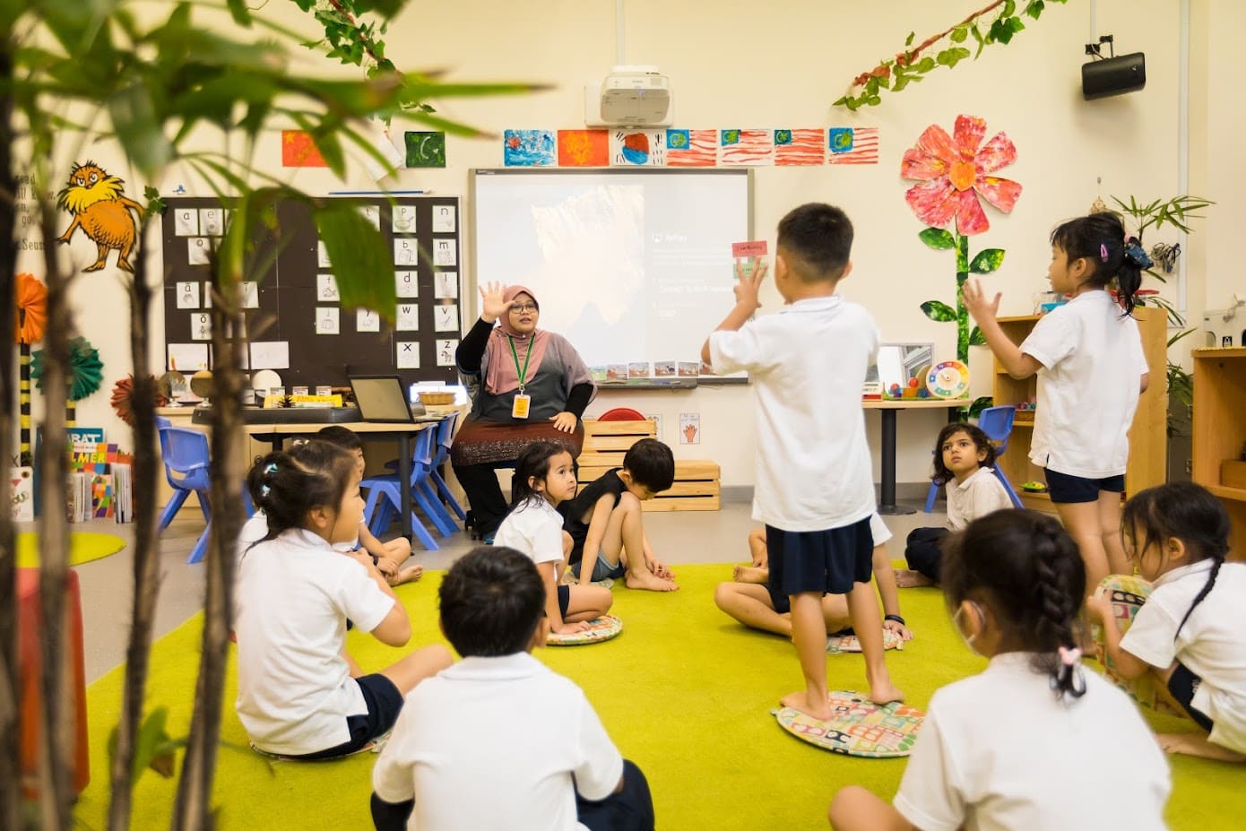 A teacher demonstrating sign language to students, promoting skill development and curriculum enrichment in a classroom setting.